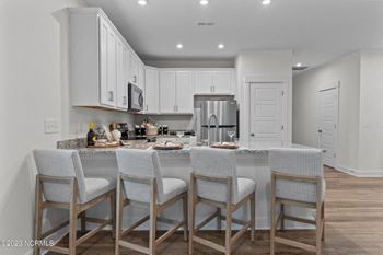 a kitchen with white cabinets and a large island with four chairs